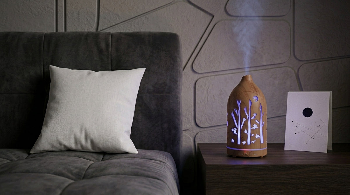 Light wood grain forest cutout diffuser emitting a cool blue LED light on a dark wooden nightstand in a modern bedroom with geometric wall panels and a constellation card.